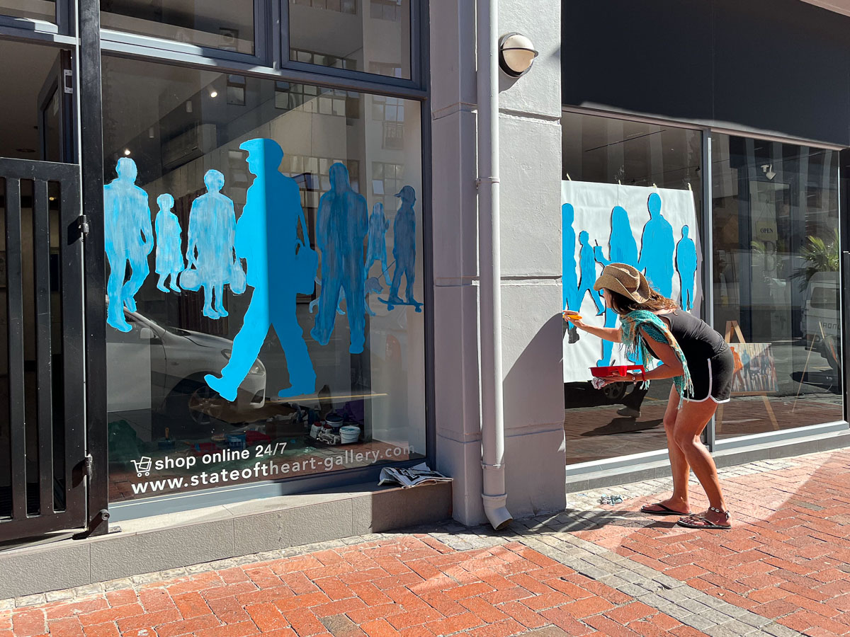 Tharien Smith working on her mural on the shop windows